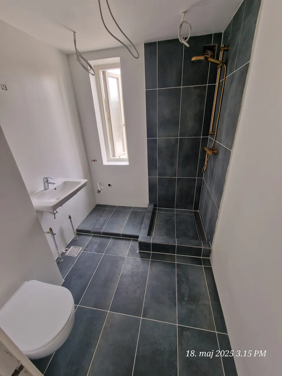 Fliselagt badeværelse med toilet og ovenlys